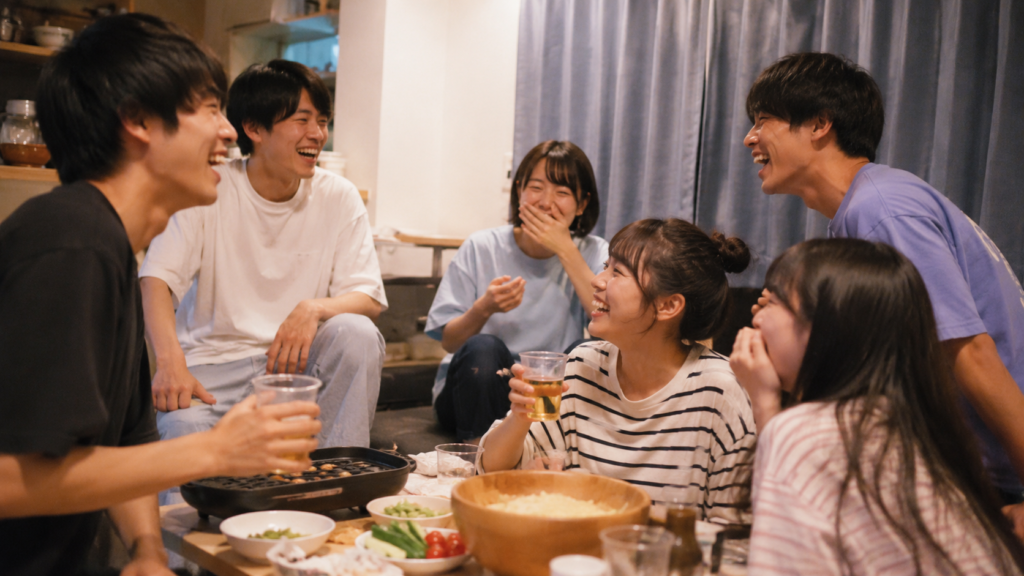 大学生の仲間たちが食事を囲んで盛り上がる青春コメディのイメージ